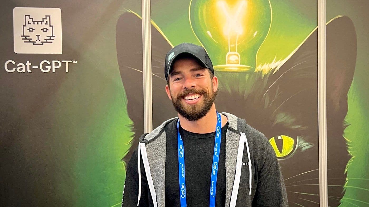 Adam Bragg at CatCon, in front of the Cat-GPT booth